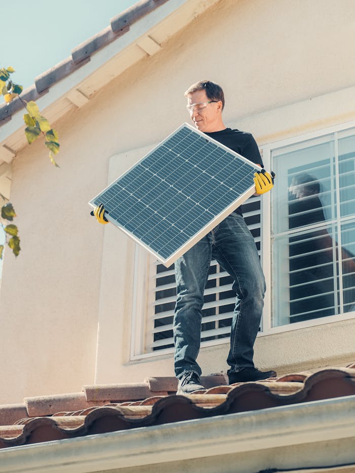 A technician is installing a solar panel on a house roof, promoting clean energy solutions.